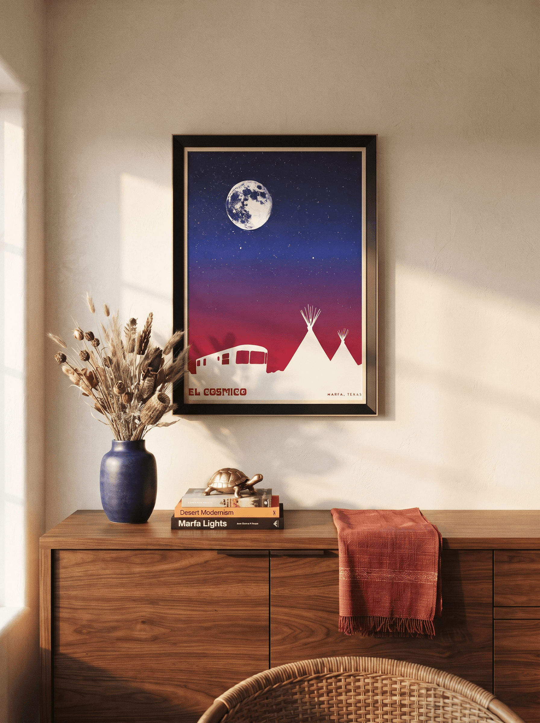 Gabriela's framed El Cosmico Marfa print in a black frame with a thin light inner lip, on a warm plaster wall above a walnut console