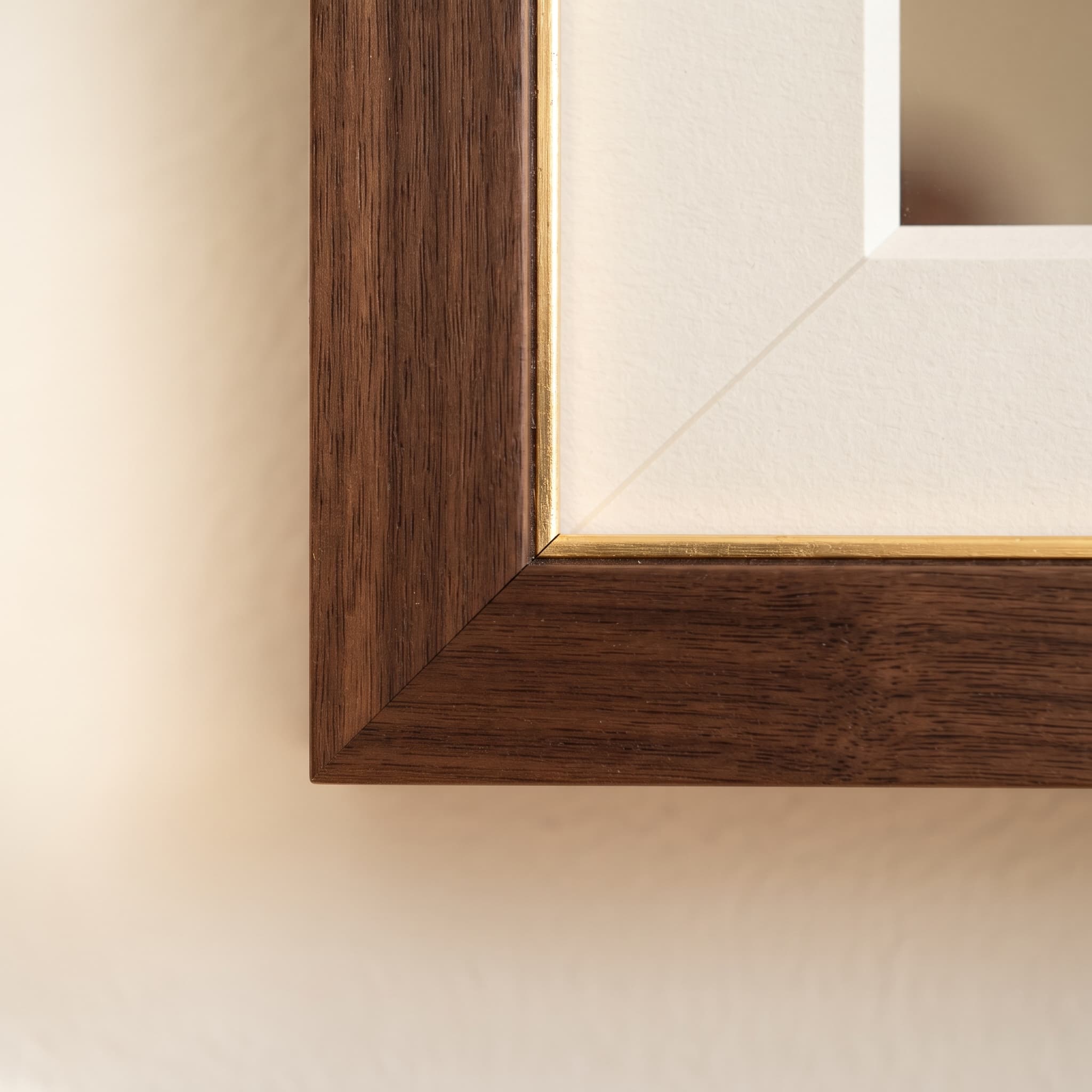 Close-up of a walnut frame corner with a gilt inner lip and an ivory museum mat bevel